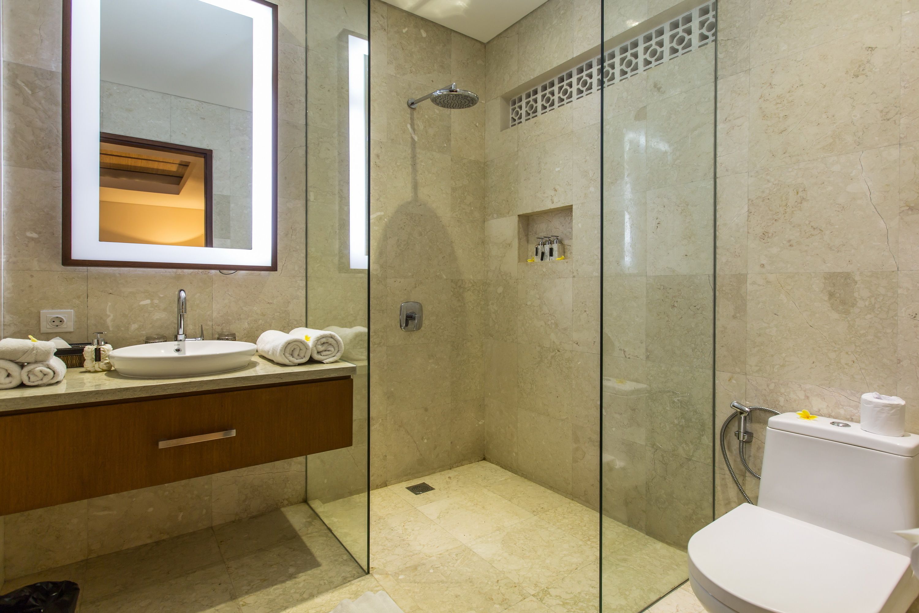 A modern bathroom with a glass-enclosed shower, a sink with a mirror, and a toilet.