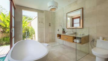 Un baño moderno con una bañera independiente, una cabina de ducha de vidrio, un tocador de madera y un espejo grande.