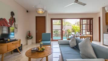 Una sala de estar moderna con un sofá, una mesa de centro, televisor y un comedor con mesa y sillas.
