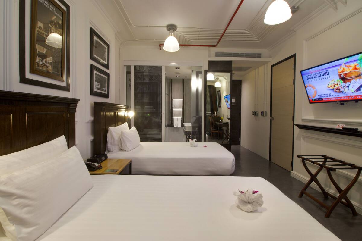 A hotel room with two beds, a TV, and a wooden headboard.