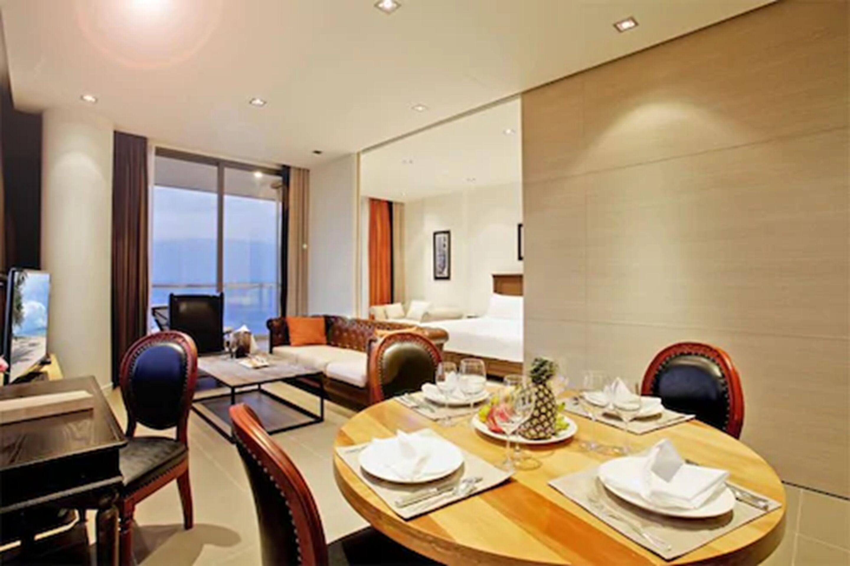 Una habitación de hotel con comedor, sofá, cama y un ventanal grande.