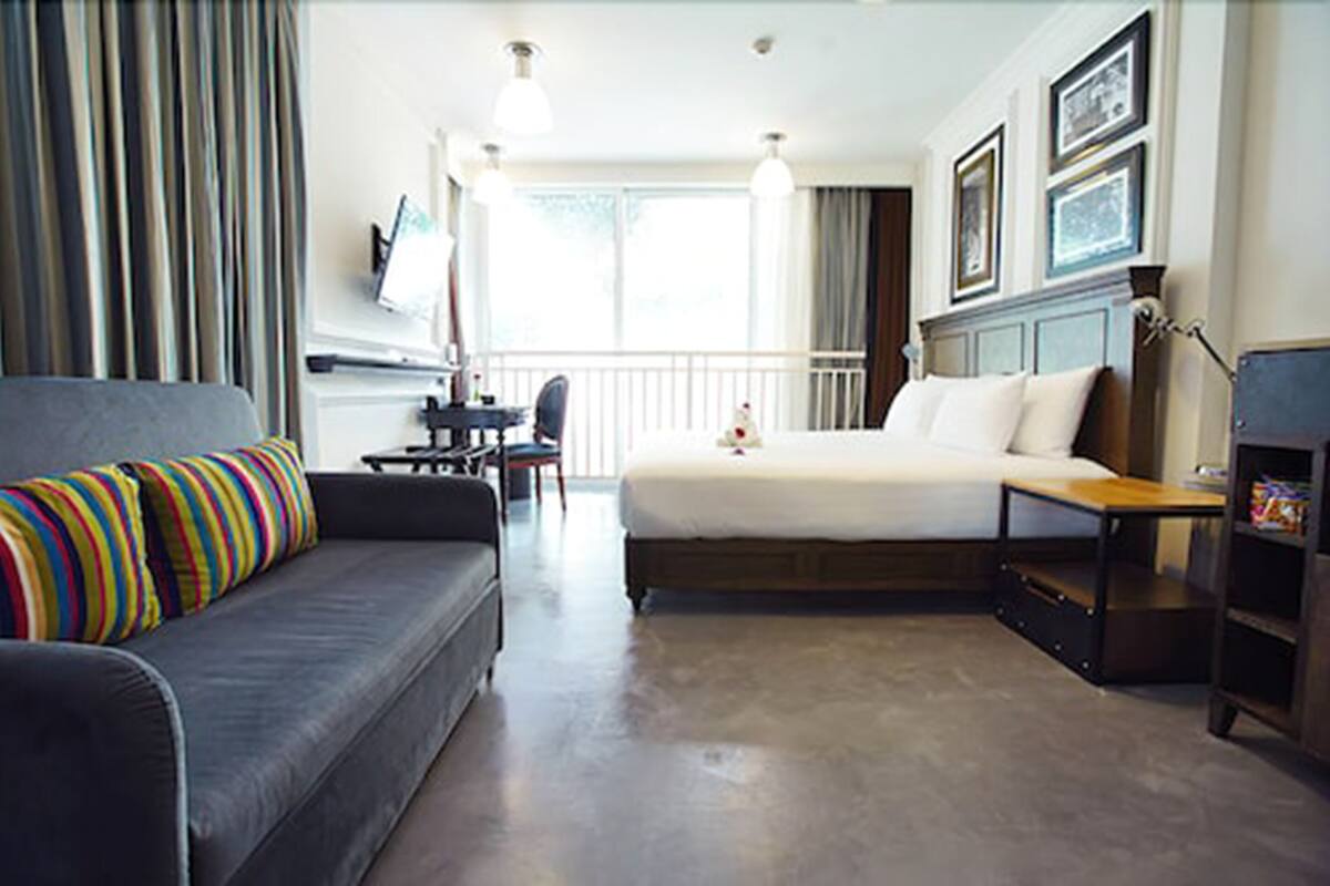 A hotel room with a bed, a sofa, a desk, and a chair.