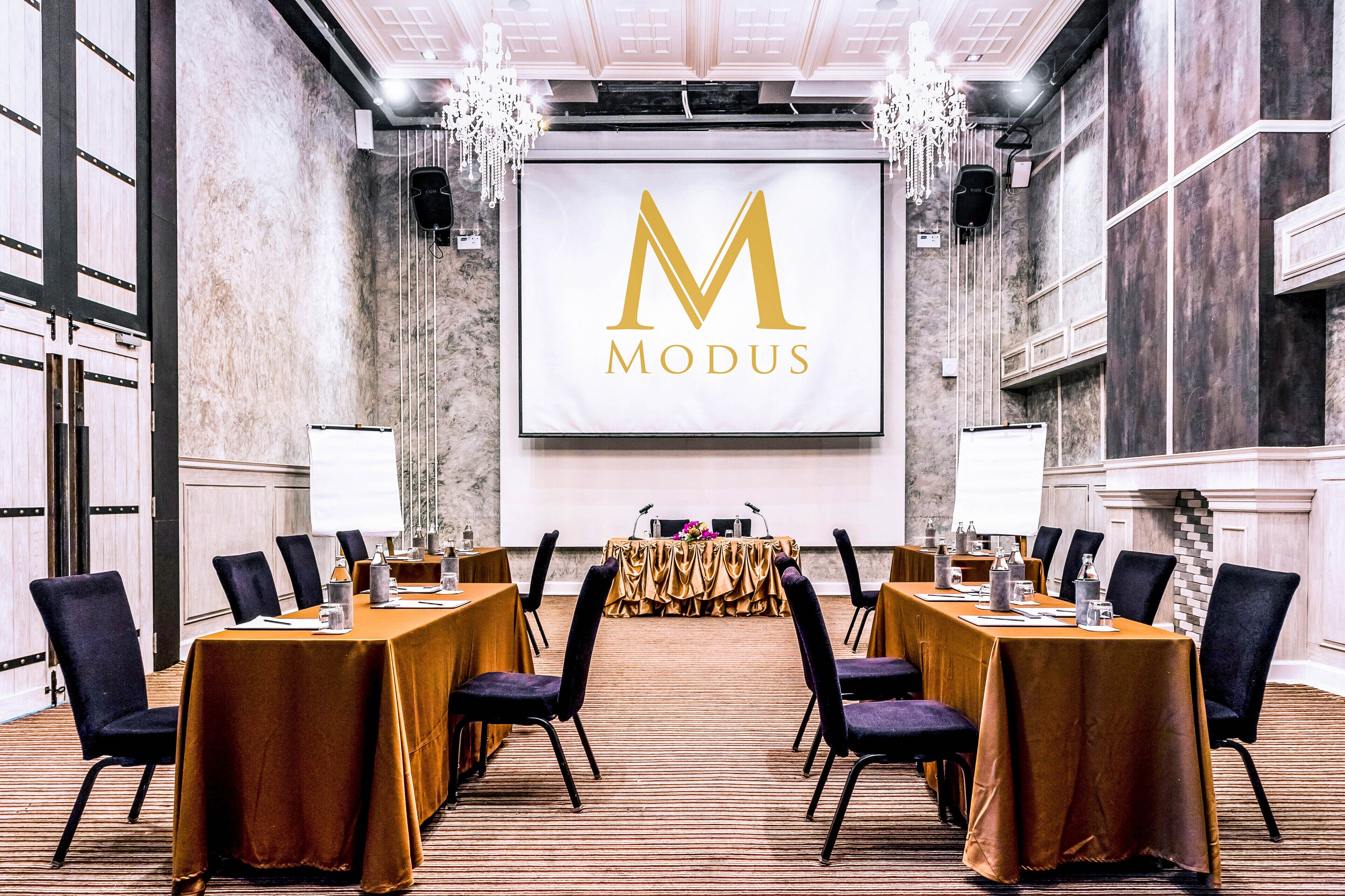 A conference room with a long table, chairs, a projector screen, and a chandelier.