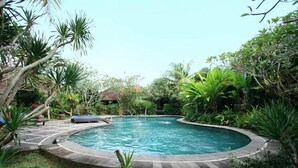 Una piscina circular rodeada de exuberante vegetación y una terraza de piedra.
