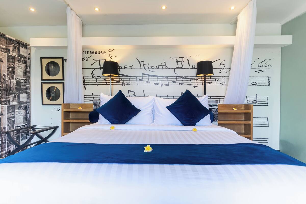 A neatly made bed with a blue bedspread, white pillows, and two black lamps on either side.