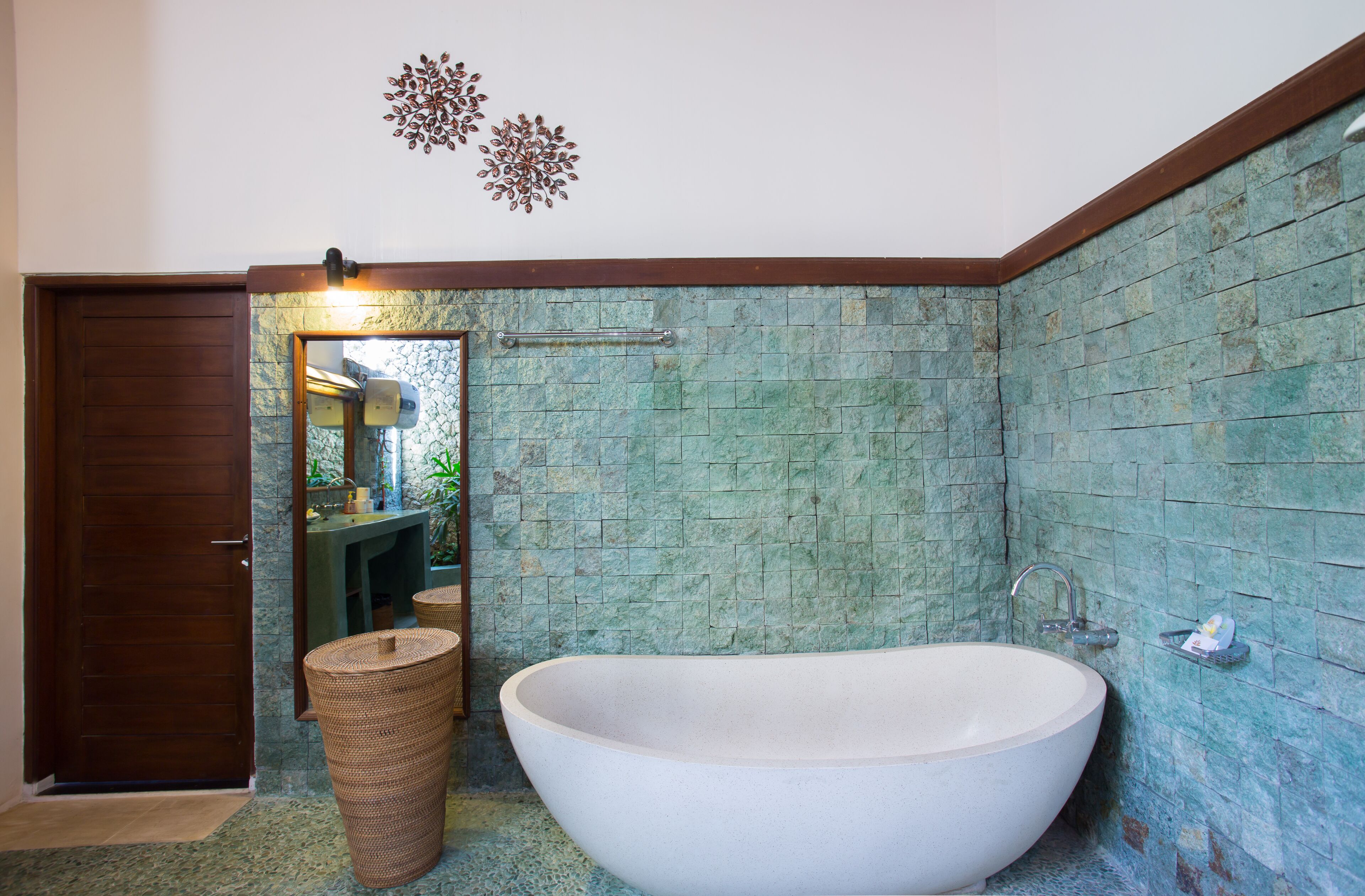 Ein Badezimmer mit freistehender Badewanne, einer Holztür und einem Spiegel mit Beleuchtung darüber.