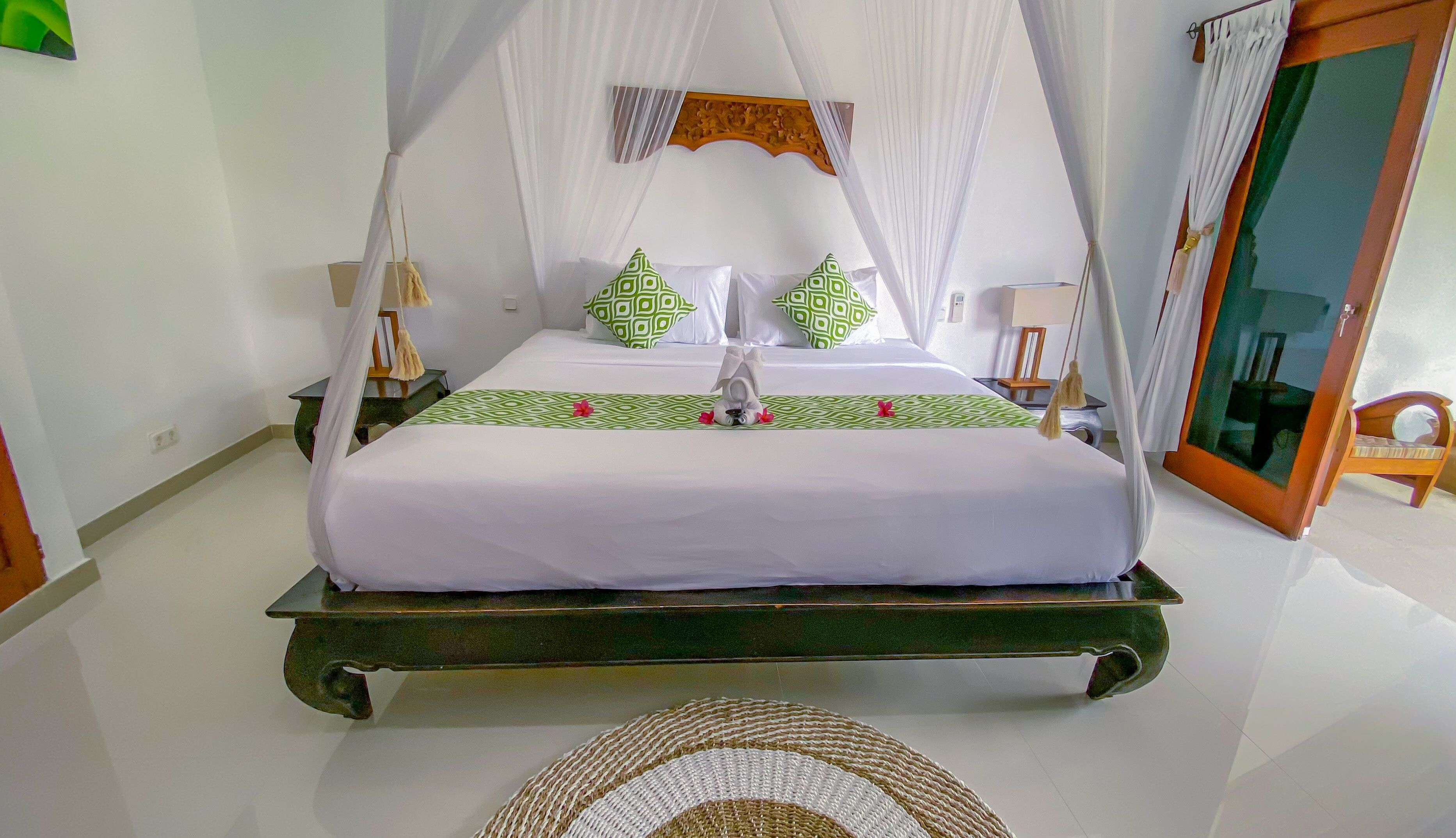 Una cama con dosel, colcha estampada verde y almohadas.