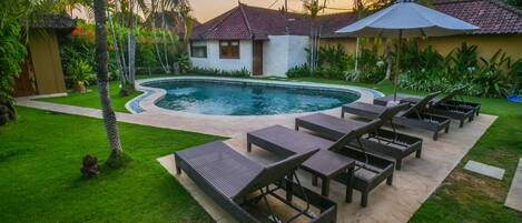 Une piscine avec des chaises longues et un espace patio.