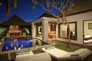 A modern outdoor pool area with lounge chairs, a dining area, and a well-lit interior space. - The Haere Seminyak - By Astadala (Keroboken Kelod)