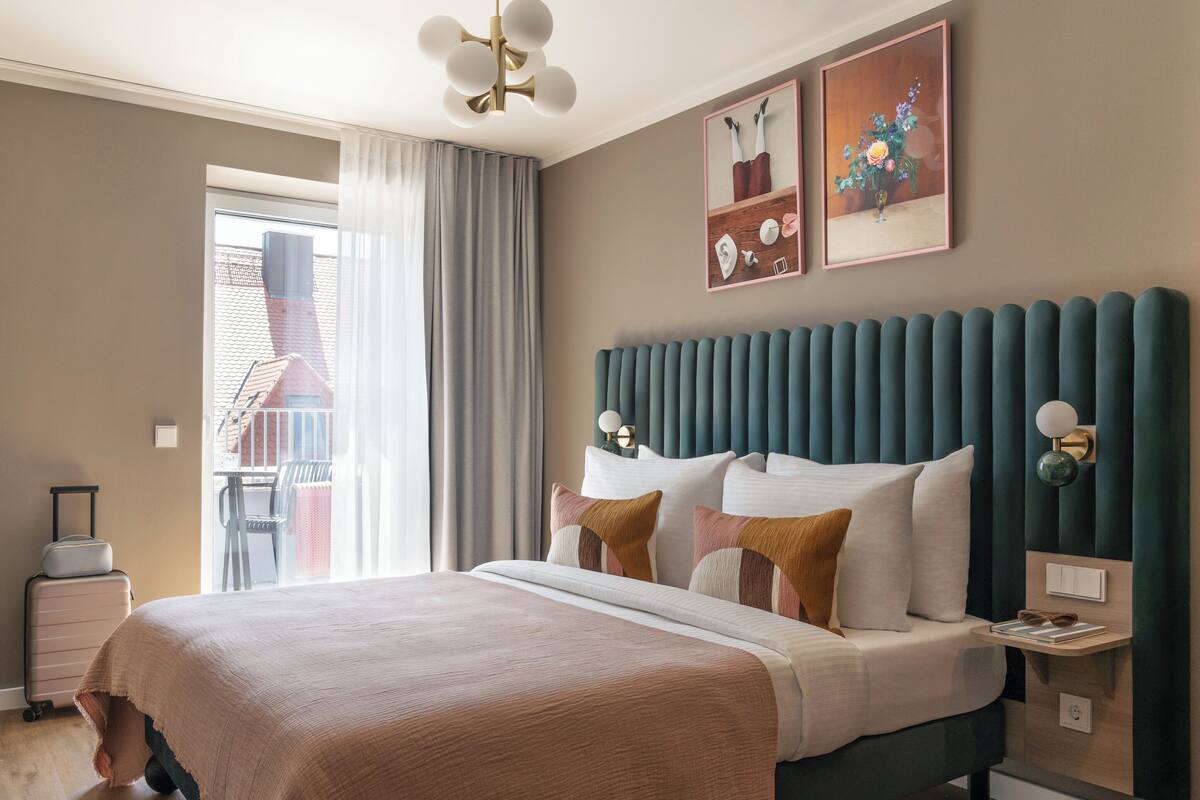Una habitación de hotel moderna con una cama grande, vistas al exterior y un balcón.