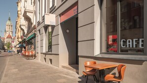 A street view with a cafe named "Numa" on the corner, featuring outdoor seating with chairs and a table. - Numa Munich St Paul (Munich)