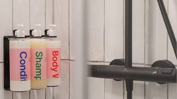 Three bottles of body wash on a wall-mounted rack in a bathroom.