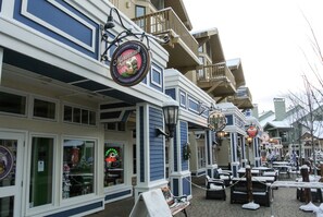 A building with a blue and white exterior, outdoor seating area with tables and chairs, and a sign that reads "Mountain Sage."