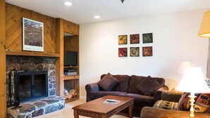 A cozy living room with a stone fireplace, a leather sofa, and a coffee table. - Vantage Point Villas at Stratton Mountain Resort (Stratton)