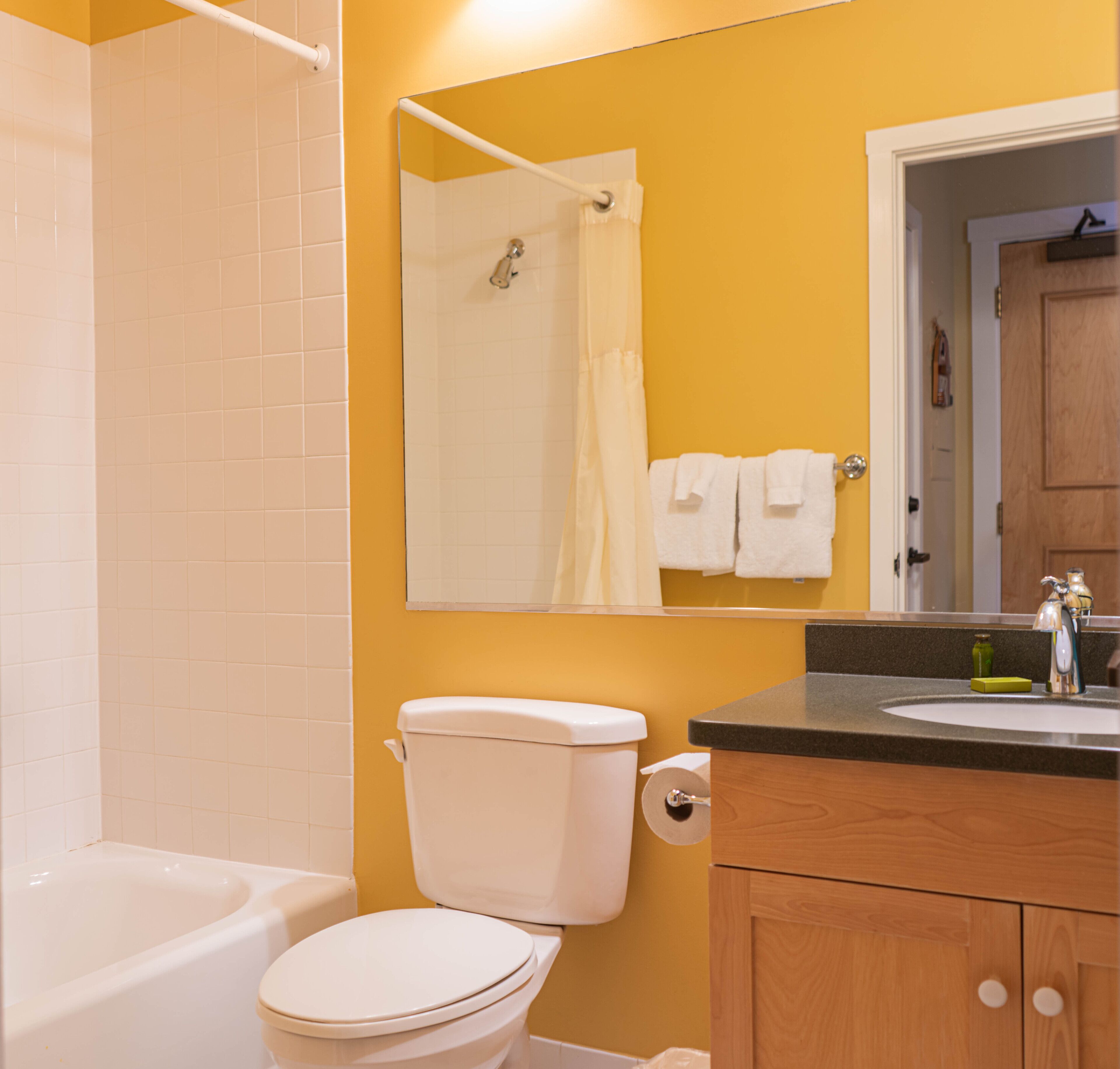 A bathroom with a bathtub, toilet, sink, and a mirror.