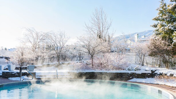 A swimming pool with a stone border, surrounded by a snow-covered landscape and a wooden fence. - Long Trail House at Stratton Mountain Resort (Stratton)