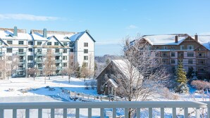 A snow-covered landscape with a wooden cabin and modern buildings. - Long Trail House at Stratton Mountain Resort (Stratton)