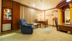 Une pièce comprenant un fauteuil bleu inclinable, une petite table avec des chaises, un bureau et un miroir.