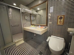 Un baño con piso a rayas, un lavamanos con espejo, un inodoro y una zona de ducha.