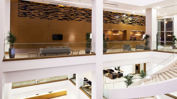 A multi-level hotel lobby with a central staircase, seating areas, and a reception desk.