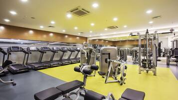 Un gimnasio con cintas de correr, máquinas de pesas y bancos.