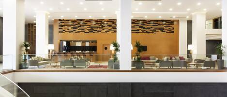 A modern lobby with a seating area, a staircase, and a wall with a geometric pattern.