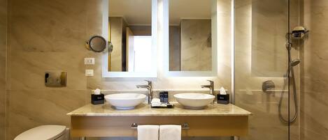 A modern bathroom with two sinks, a toilet, a shower, and a large mirror.