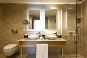 Un baño moderno con dos lavamanos, un inodoro, una ducha y un espejo grande.