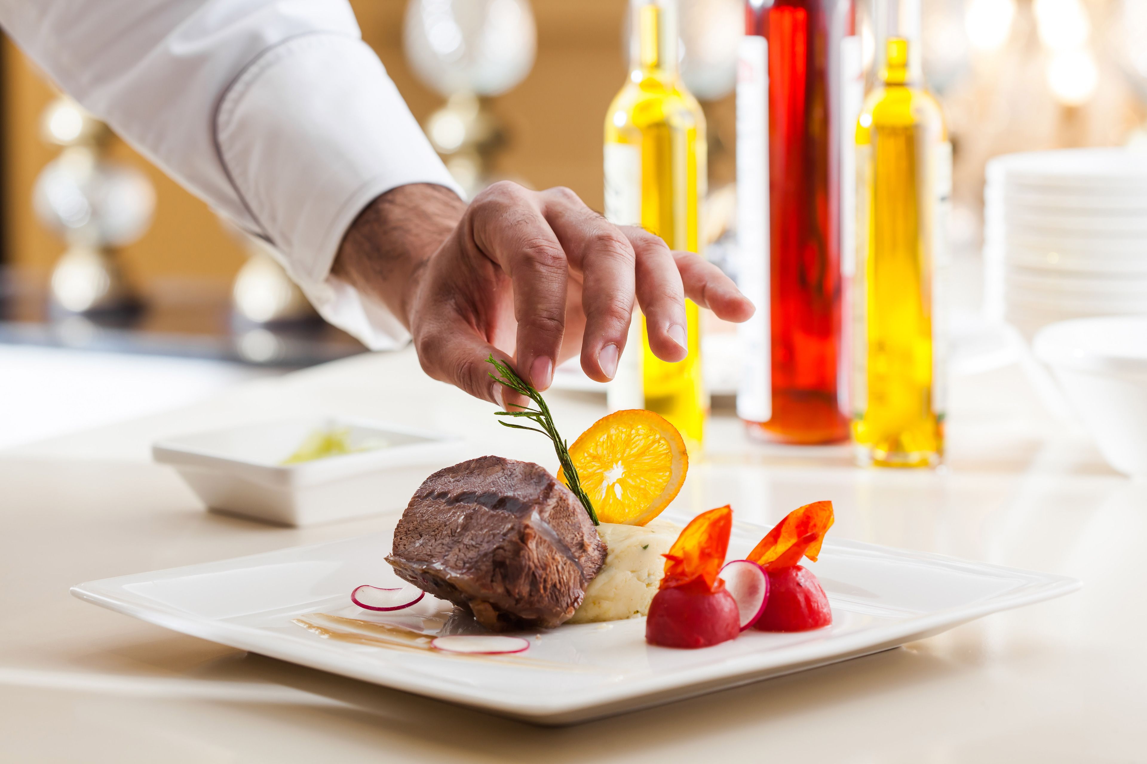 A chef placing a garnish on a dish.