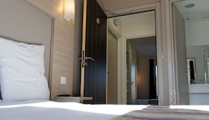 A hotel room with a bed, a bedside table, a wardrobe, and a bathroom visible through an open door. - Hôtel Restaurant l'Echo du Lac & Spa (Gerardmer)