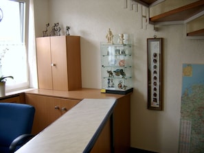 A room with a wooden desk, a blue chair, a glass display case with figurines, and a framed picture on the wall. - Hotel Bürgerhaus (Steinbach)