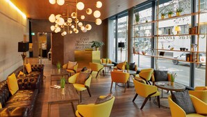 Ein modernes Interieur mit Ledersofas, gelben Sesseln, Holztischen und einem großen Fenster mit Blick auf die Straße.