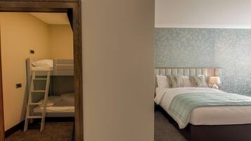 A room with a bunk bed, a ladder, a bedside table with a lamp, and a patterned wall.
