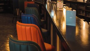 Zona de bar con diversas opciones de asientos, barra y lámparas colgantes.