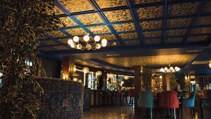 Zona de bar con techo decorado, múltiples lámparas colgantes y diferentes tipos de asientos.