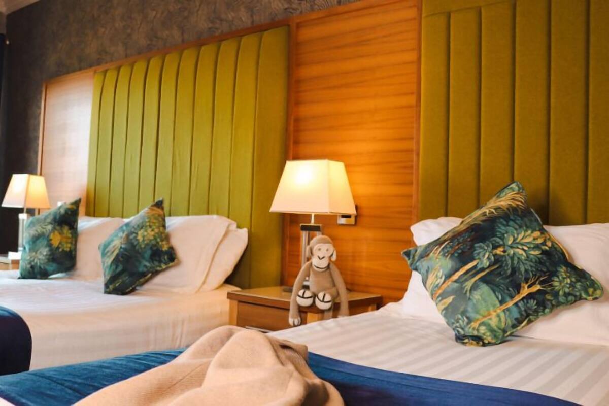 Ein Hotelzimmer mit zwei Betten, jeweils einem Nachttisch, Lampen und dekorativen Kissen.