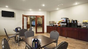 Une chambre d’hôtel dotée d’un coin repas, d’un téléviseur à écran plat fixé au mur et d’une kitchenette équipée d’une machine à café et de divers appareils électroménagers.