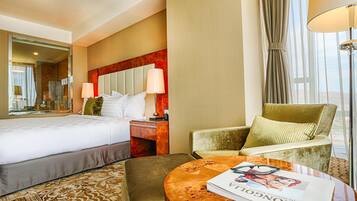 Una habitación de hotel con cama, mesita de noche, lámpara, silla y una mesa con una revista.