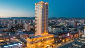 Un immeuble de grande hauteur, doté d’une architecture remarquable au niveau de son angle, et entouré d’autres bâtiments au sein d’un paysage urbain.