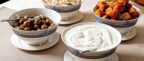 A table with four bowls of food, each with a spoon.