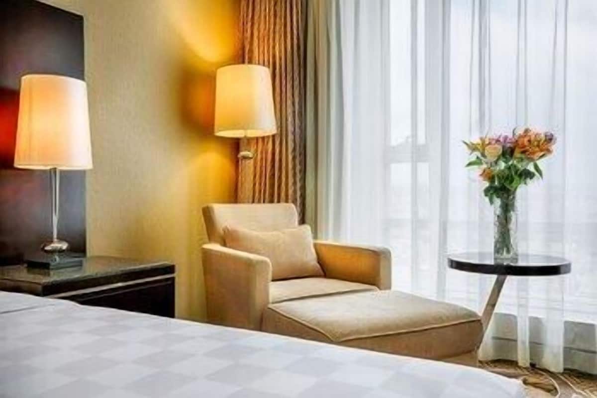 Et hotelværelse med en seng, en sofa, et bord med en vase blomster og to lamper.