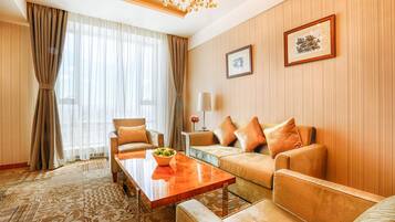 A modern hotel room with a sofa set, a wooden coffee table, and a patterned carpet.