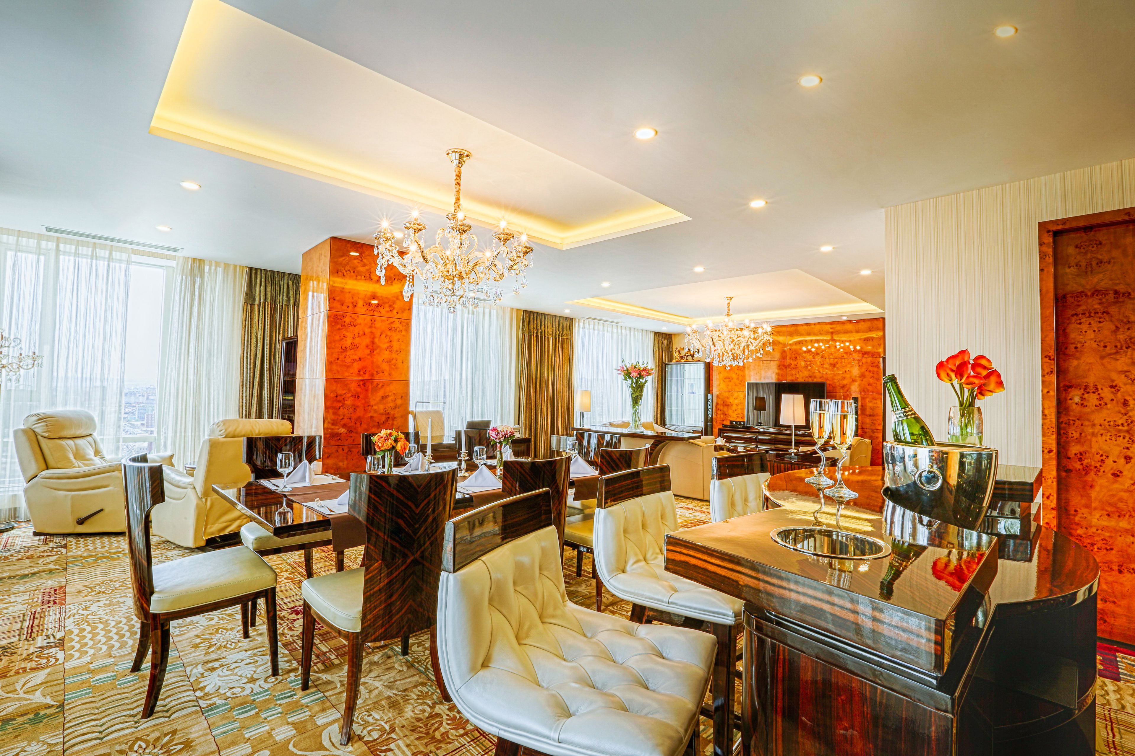 A hotel lobby with a chandelier, seating area, and a television.