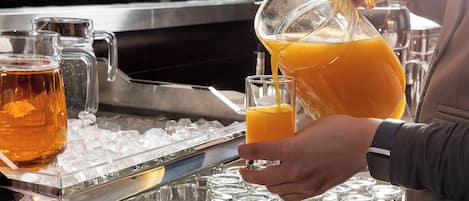 A person pouring orange juice into a glass.