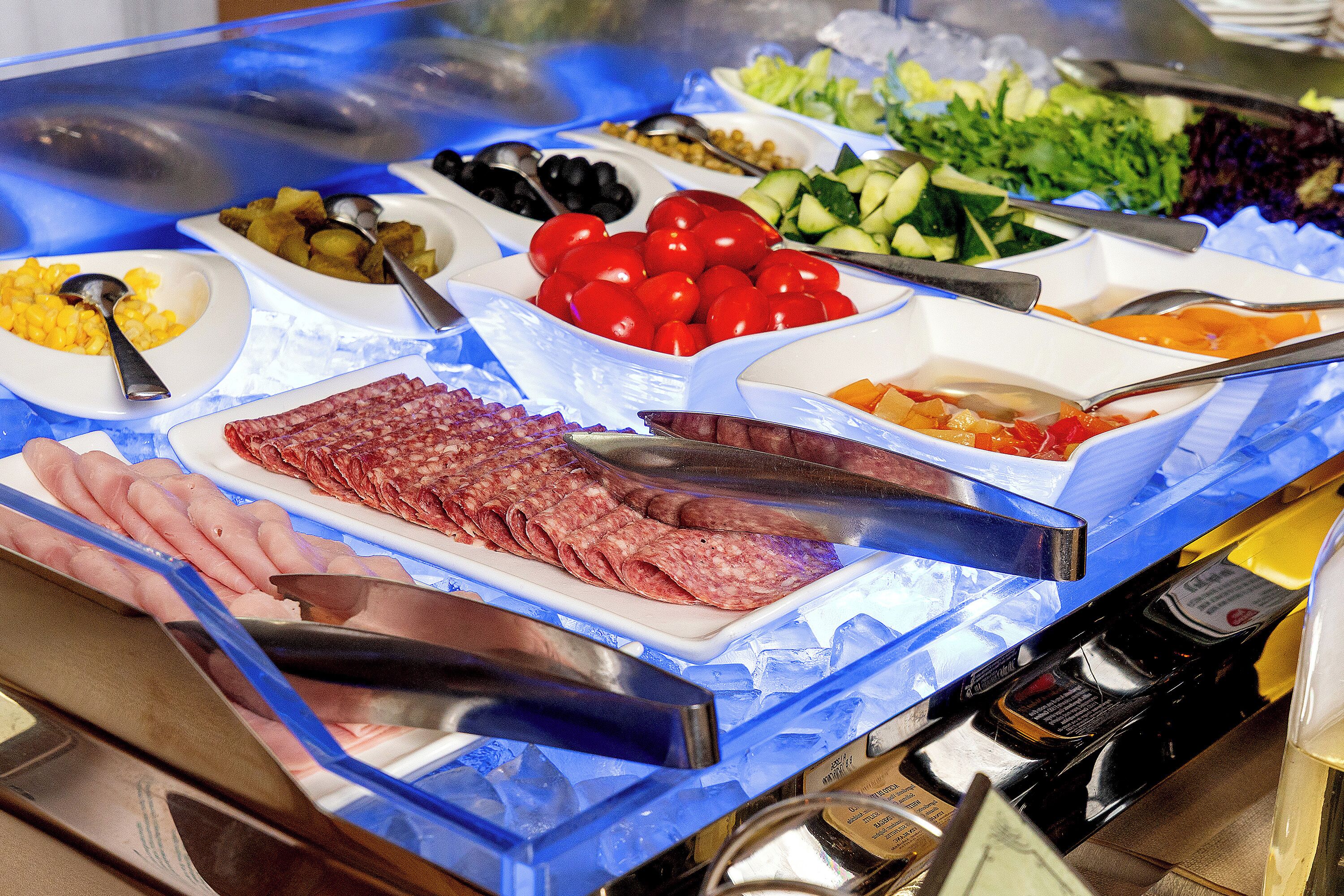 Ein reichhaltiges Buffet mit verschiedenen Speisen, darunter Fleisch, Gemüse und Obst.