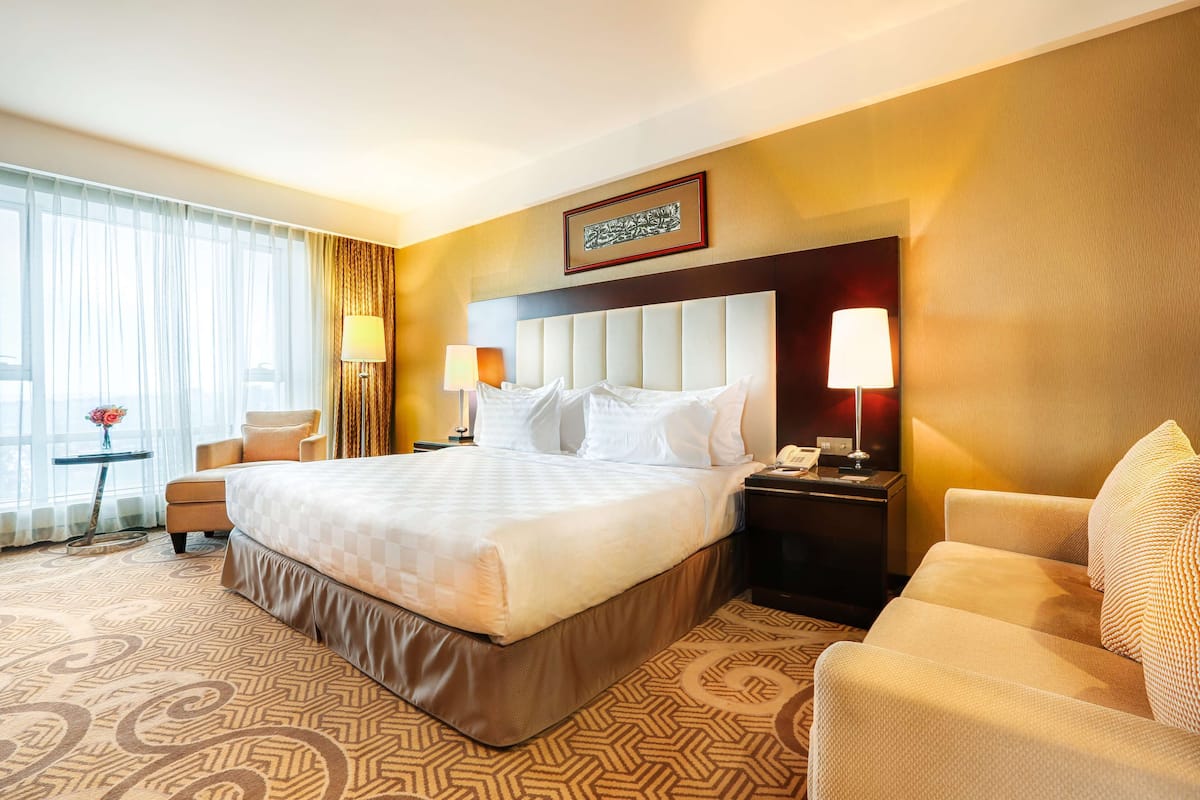 Relax in a cozy retreat with a large bed, a small table, and a comfortable chair.