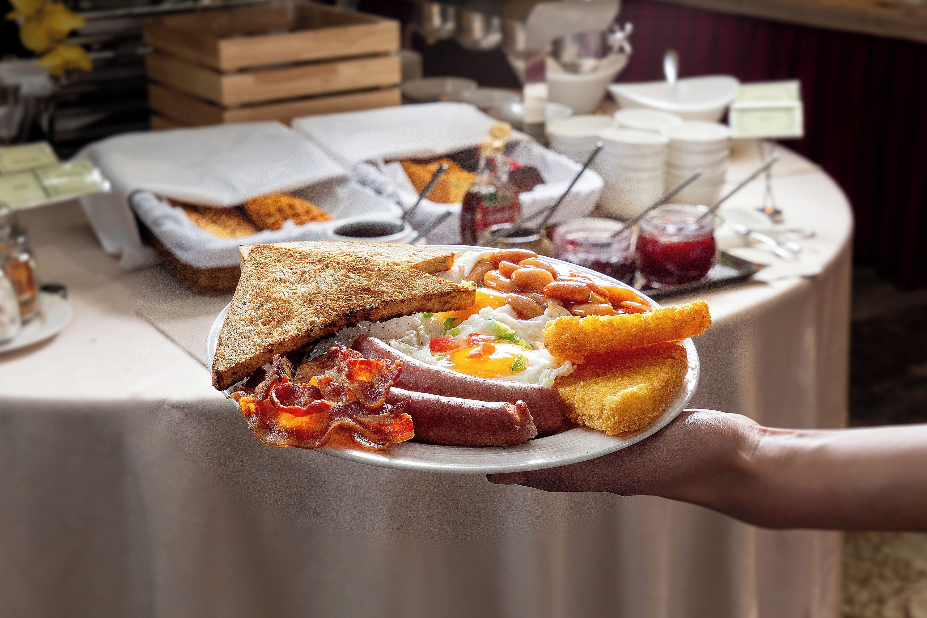 A breakfast plate with toast, bacon, sausages, eggs, and toast.
