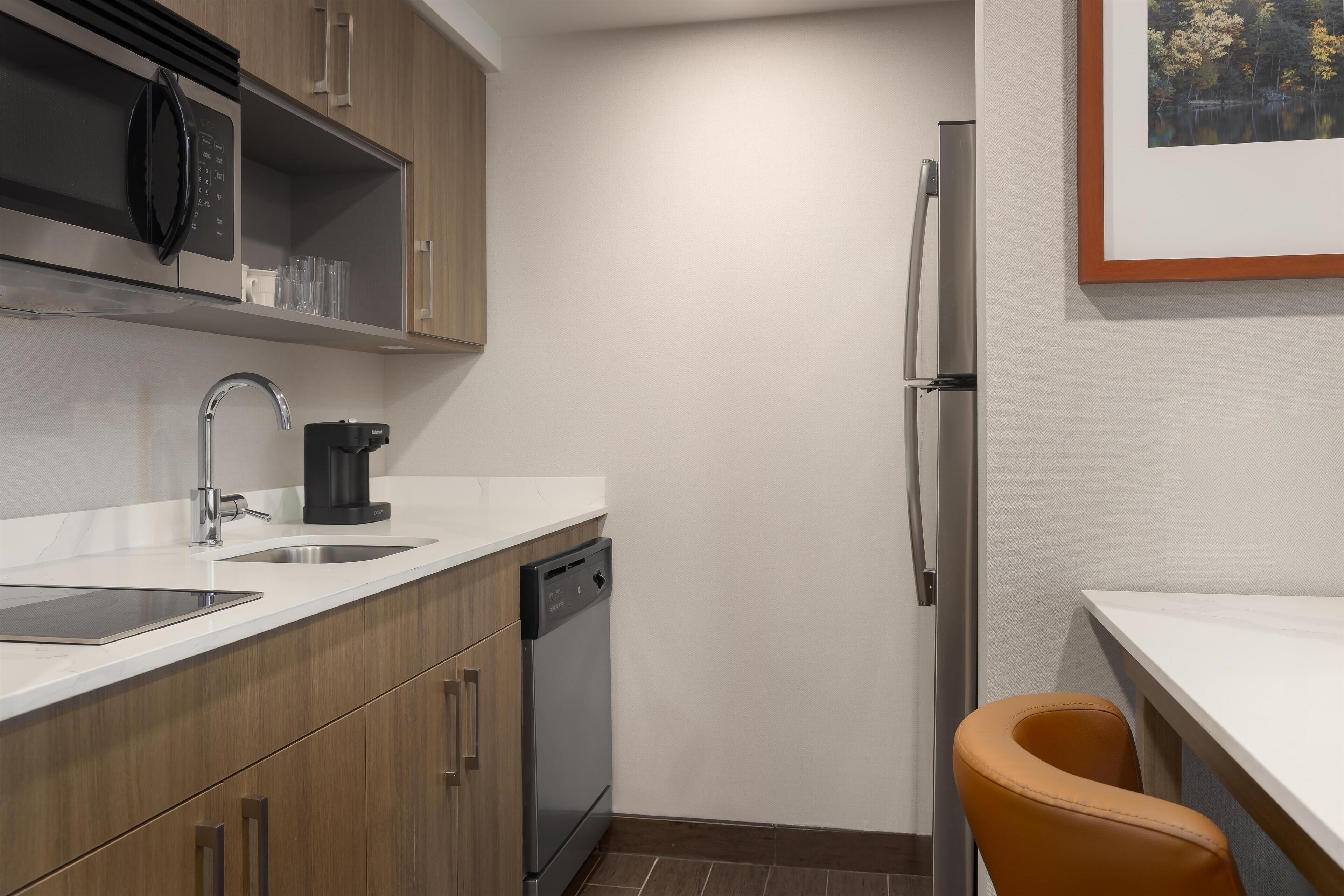 A compact kitchen with a dishwasher, a coffee maker, and a refrigerator.