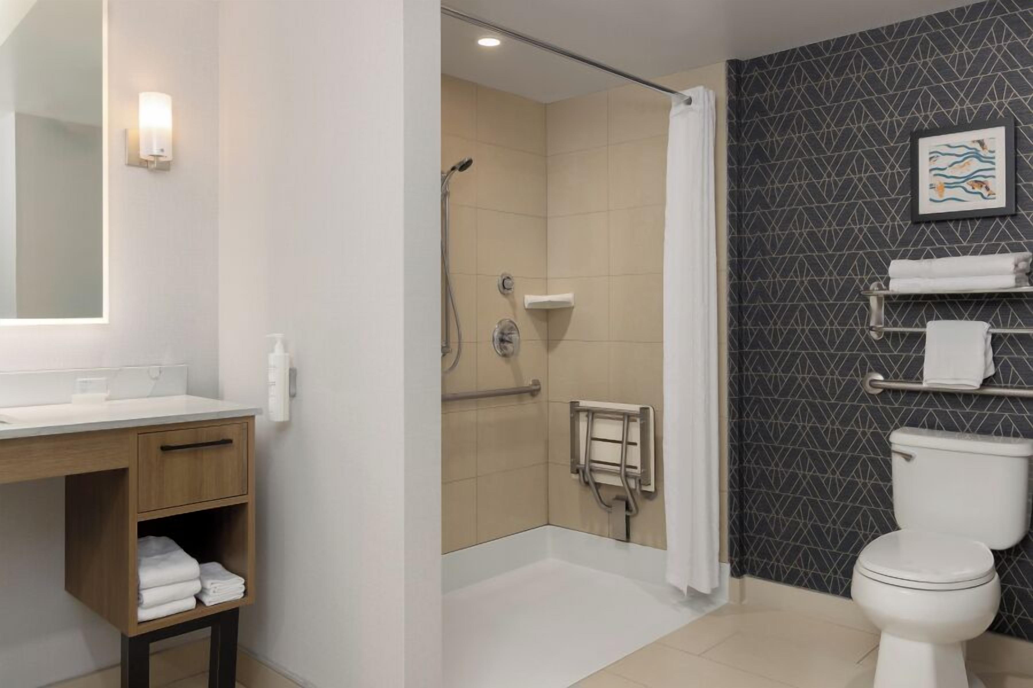 A modern bathroom with a shower, toilet, and sink.