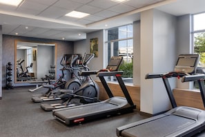 A gym with treadmills, ellipticals, and a mirror.